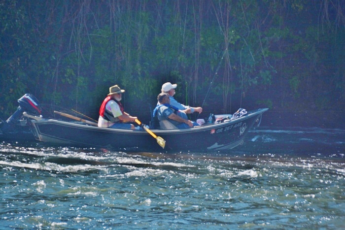 three men in boat on river